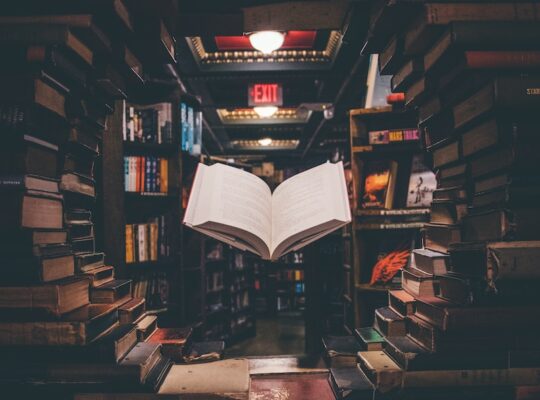 view of floating open book from stacked books in library