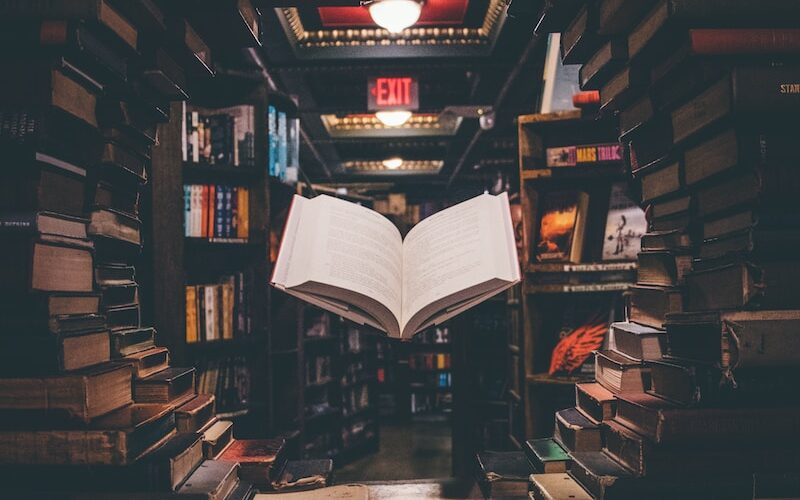 view of floating open book from stacked books in library