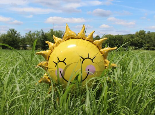 yellow inflatable sun at grass field